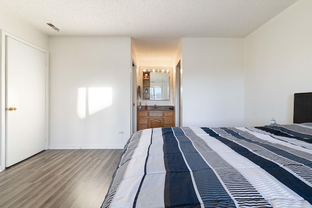 unfurnished bedroom featuring wood-type flooring, connected bathroom, a textured ceiling, and sink