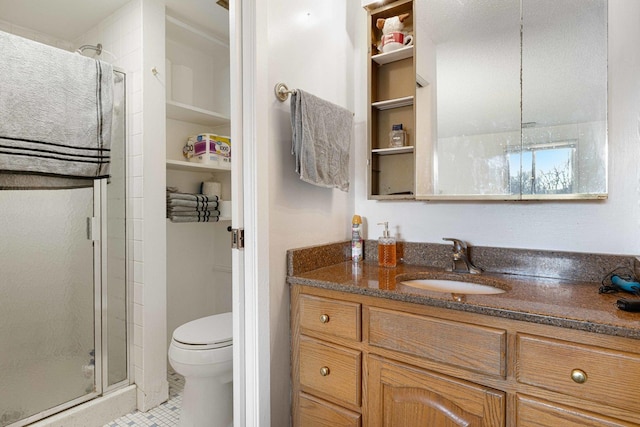 bathroom with tile patterned flooring, vanity, a shower with shower door, and toilet