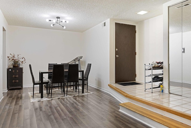 dining space featuring a chandelier, a textured ceiling, and hardwood / wood-style flooring