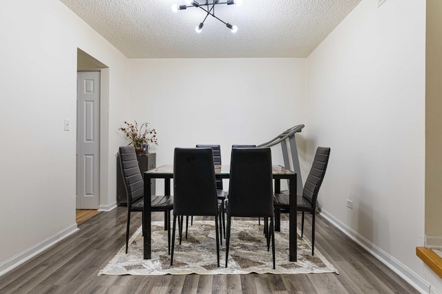 dining room with a chandelier, a textured ceiling, and dark wood-type flooring