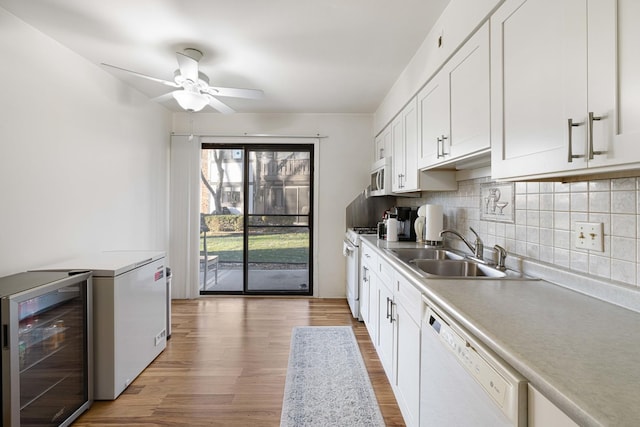 kitchen with white appliances, sink, white cabinets, light hardwood / wood-style floors, and wine cooler