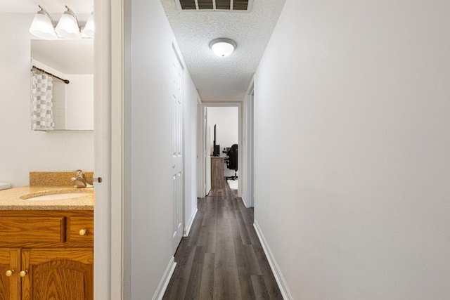 hallway featuring a textured ceiling, sink, and dark hardwood / wood-style floors