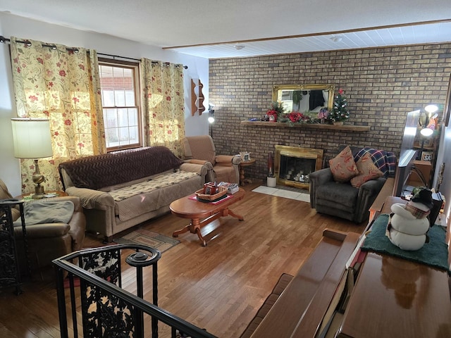 living room with wood-type flooring, brick wall, and a brick fireplace