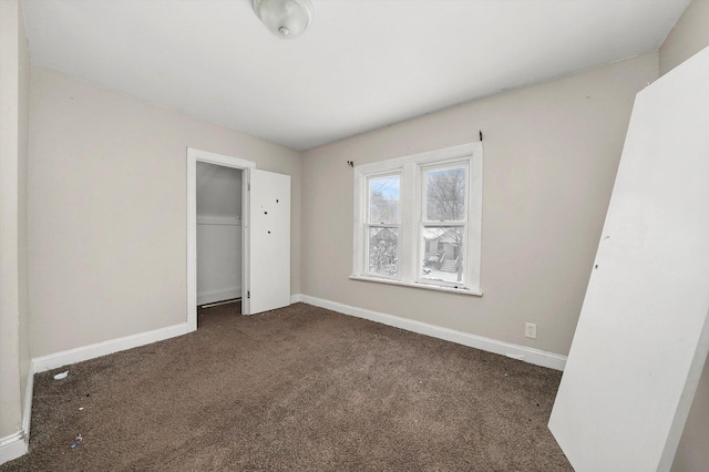 unfurnished bedroom with dark carpet and a closet