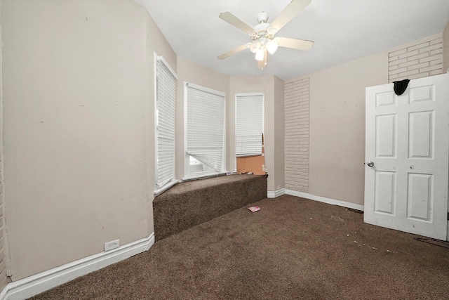 unfurnished bedroom with ceiling fan, brick wall, and dark colored carpet