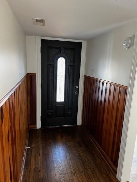 foyer featuring wooden walls and dark wood-type flooring