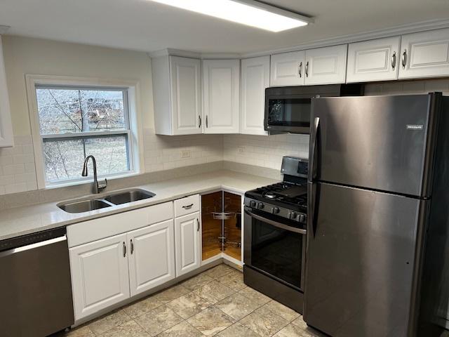 kitchen featuring black appliances, decorative backsplash, white cabinetry, and sink