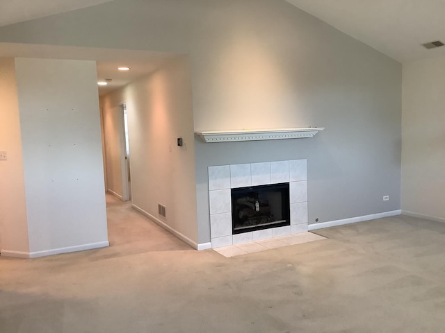 unfurnished living room with light colored carpet, a tiled fireplace, and vaulted ceiling