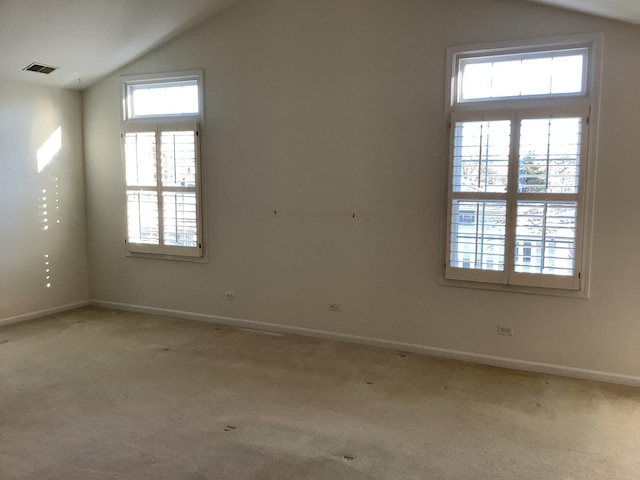 unfurnished room featuring plenty of natural light, light colored carpet, and lofted ceiling