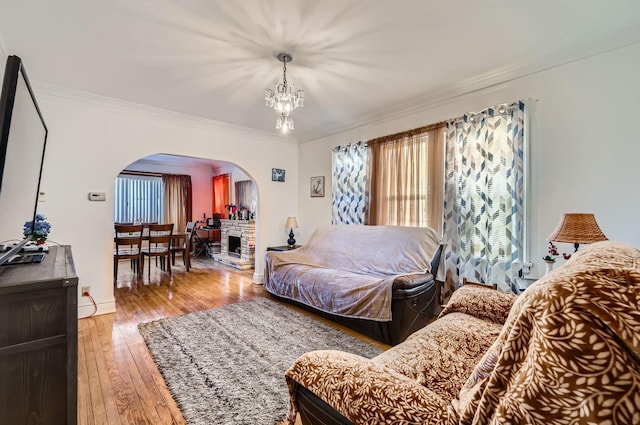 bedroom with a chandelier, a stone fireplace, ornamental molding, and light hardwood / wood-style flooring