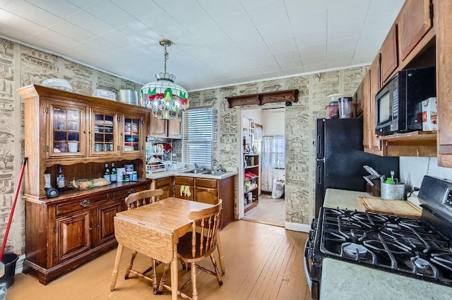 kitchen with sink, black appliances, decorative light fixtures, light hardwood / wood-style flooring, and a chandelier