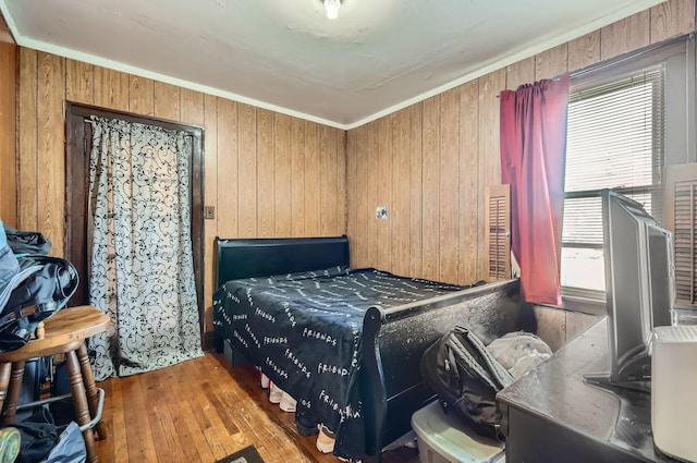 bedroom featuring light hardwood / wood-style floors, ornamental molding, and wooden walls