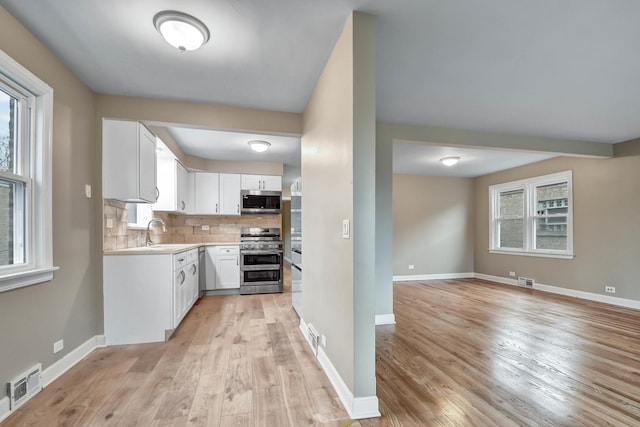 kitchen featuring white cabinetry, sink, tasteful backsplash, light hardwood / wood-style flooring, and appliances with stainless steel finishes