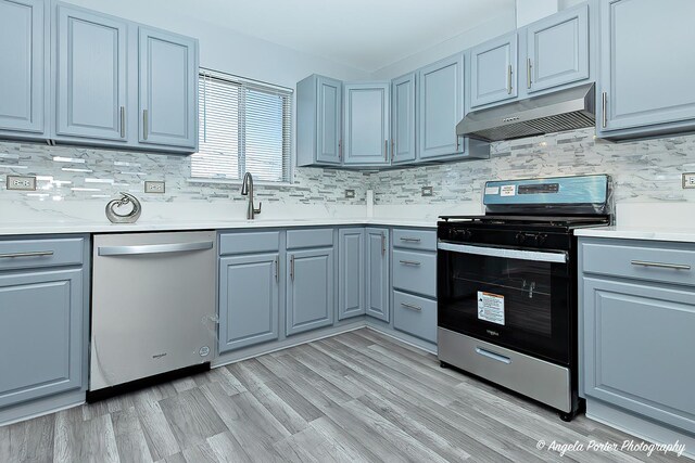 kitchen featuring appliances with stainless steel finishes, light hardwood / wood-style floors, exhaust hood, and tasteful backsplash