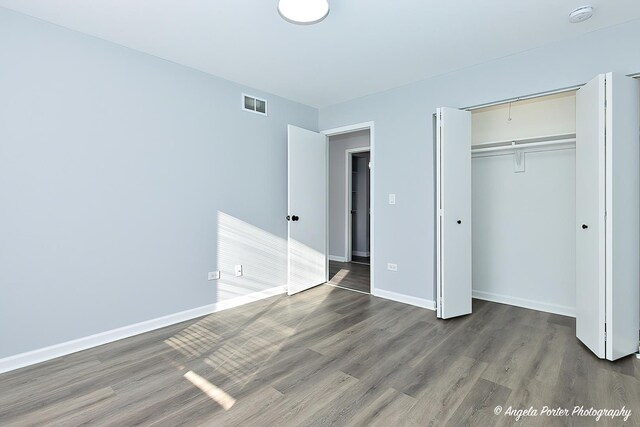 unfurnished bedroom with hardwood / wood-style flooring and a closet