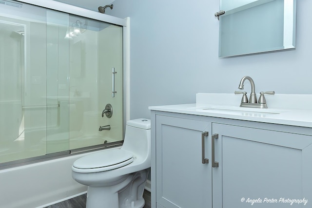 full bathroom featuring toilet, wood-type flooring, enclosed tub / shower combo, and vanity