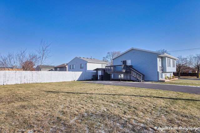 rear view of property featuring a lawn, a wooden deck, and a garage