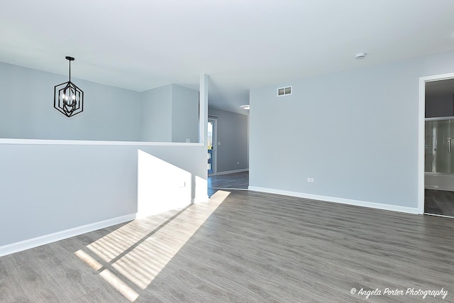 spare room featuring dark hardwood / wood-style flooring and a chandelier