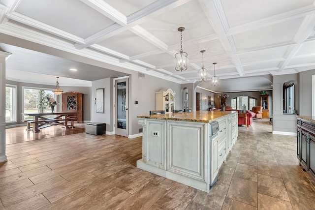 kitchen featuring an island with sink, hanging light fixtures, and coffered ceiling