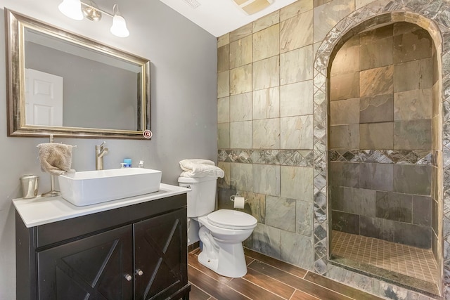 bathroom featuring tiled shower, toilet, vanity, and hardwood / wood-style flooring