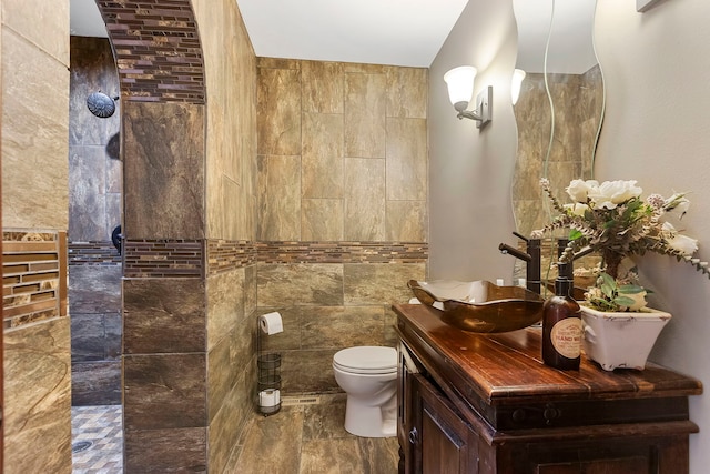 bathroom featuring vanity, toilet, and tile walls