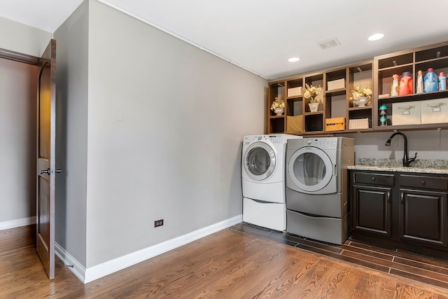 laundry room with washer and clothes dryer, dark hardwood / wood-style flooring, cabinets, and sink