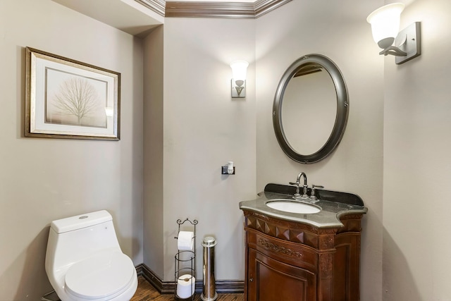 bathroom with toilet, vanity, wood-type flooring, and ornamental molding