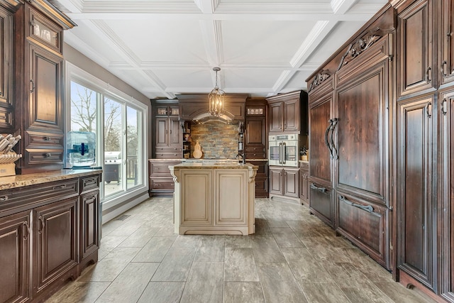 kitchen featuring cream cabinetry, a center island, hanging light fixtures, and coffered ceiling