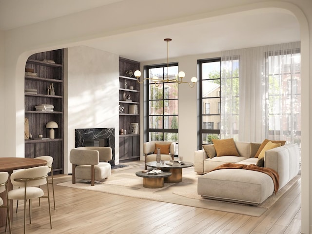 living area featuring light wood-type flooring, a high end fireplace, a notable chandelier, and built in shelves