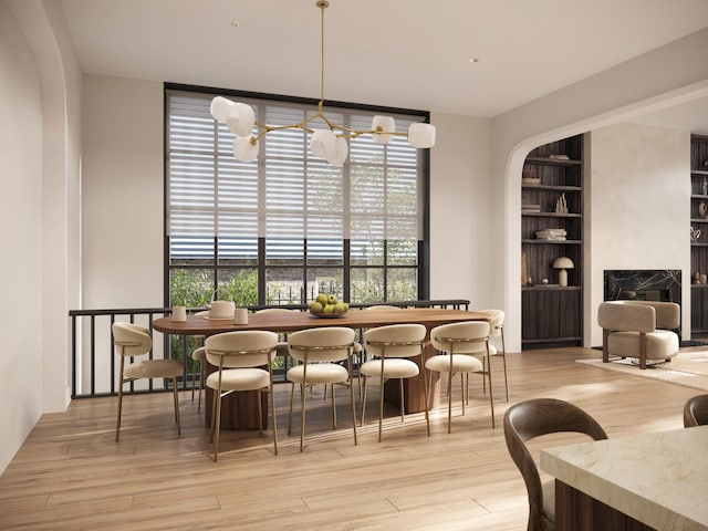 dining space featuring light wood-type flooring, built in features, and a fireplace