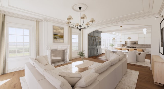 living room with light wood-type flooring, a fireplace, a wealth of natural light, and an inviting chandelier