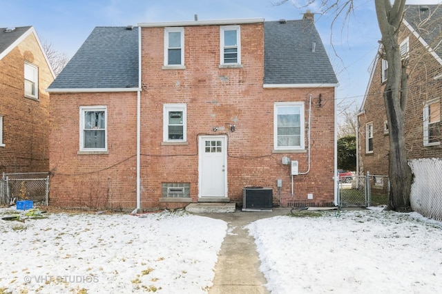 snow covered rear of property featuring central AC unit