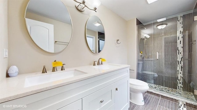 bathroom featuring vanity, a shower with shower door, and toilet