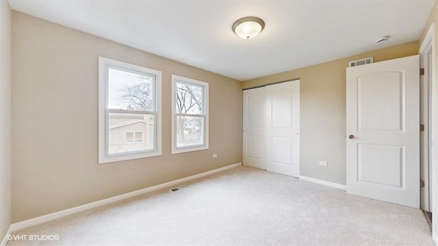 unfurnished bedroom featuring light carpet and a closet