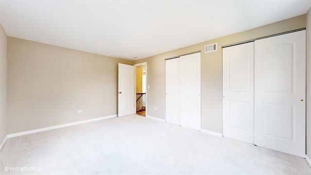 unfurnished bedroom with light carpet and two closets