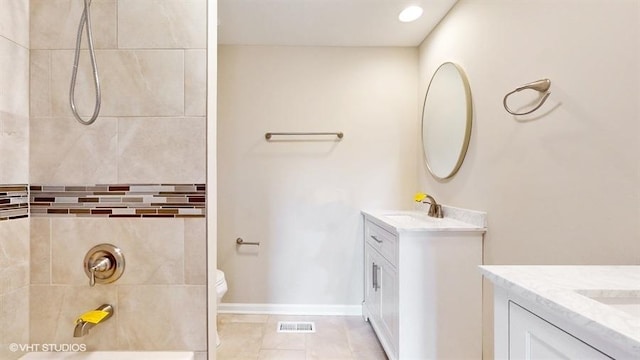 bathroom with a tile shower, tile patterned flooring, vanity, and toilet