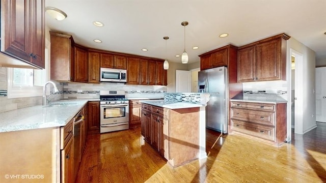 kitchen featuring pendant lighting, sink, light hardwood / wood-style flooring, a kitchen island, and stainless steel appliances