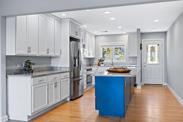 kitchen with white cabinets, a center island, light hardwood / wood-style floors, and stainless steel appliances