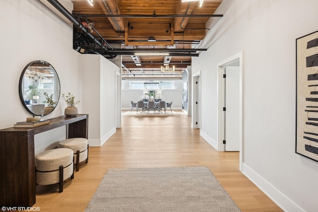 hall with light wood-style floors and baseboards