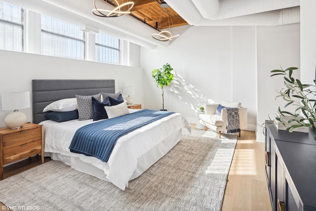 bedroom featuring light wood-style floors, baseboards, and an inviting chandelier