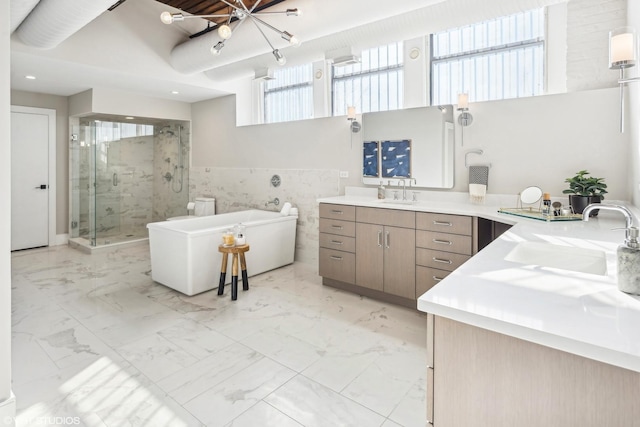 bathroom featuring a stall shower, marble finish floor, a freestanding bath, vanity, and tile walls