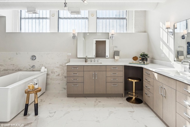 bathroom with marble finish floor, a freestanding tub, vanity, and tile walls