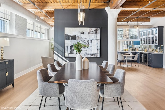 dining area with light wood-type flooring, wood ceiling, a healthy amount of sunlight, and beamed ceiling