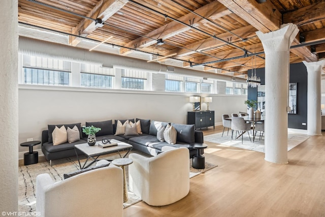 living area with baseboards, light wood-style floors, and ornate columns