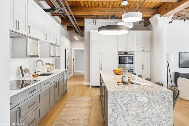 kitchen featuring hanging light fixtures, stainless steel double oven, white cabinetry, a sink, and black electric cooktop