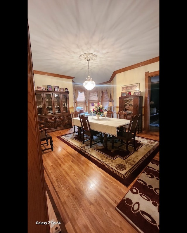 dining room featuring crown molding, a chandelier, and hardwood / wood-style flooring