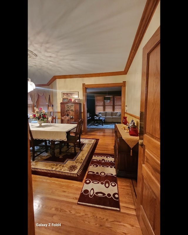 dining space featuring light hardwood / wood-style floors, crown molding, and a chandelier