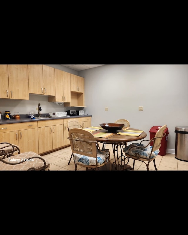 kitchen with light brown cabinets, light tile patterned floors, and sink