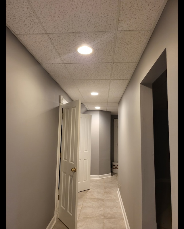 corridor featuring a drop ceiling and light tile patterned floors