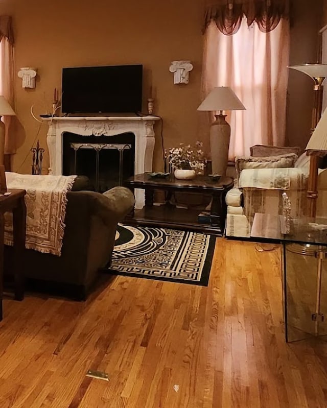 sitting room with a high end fireplace and light wood-type flooring